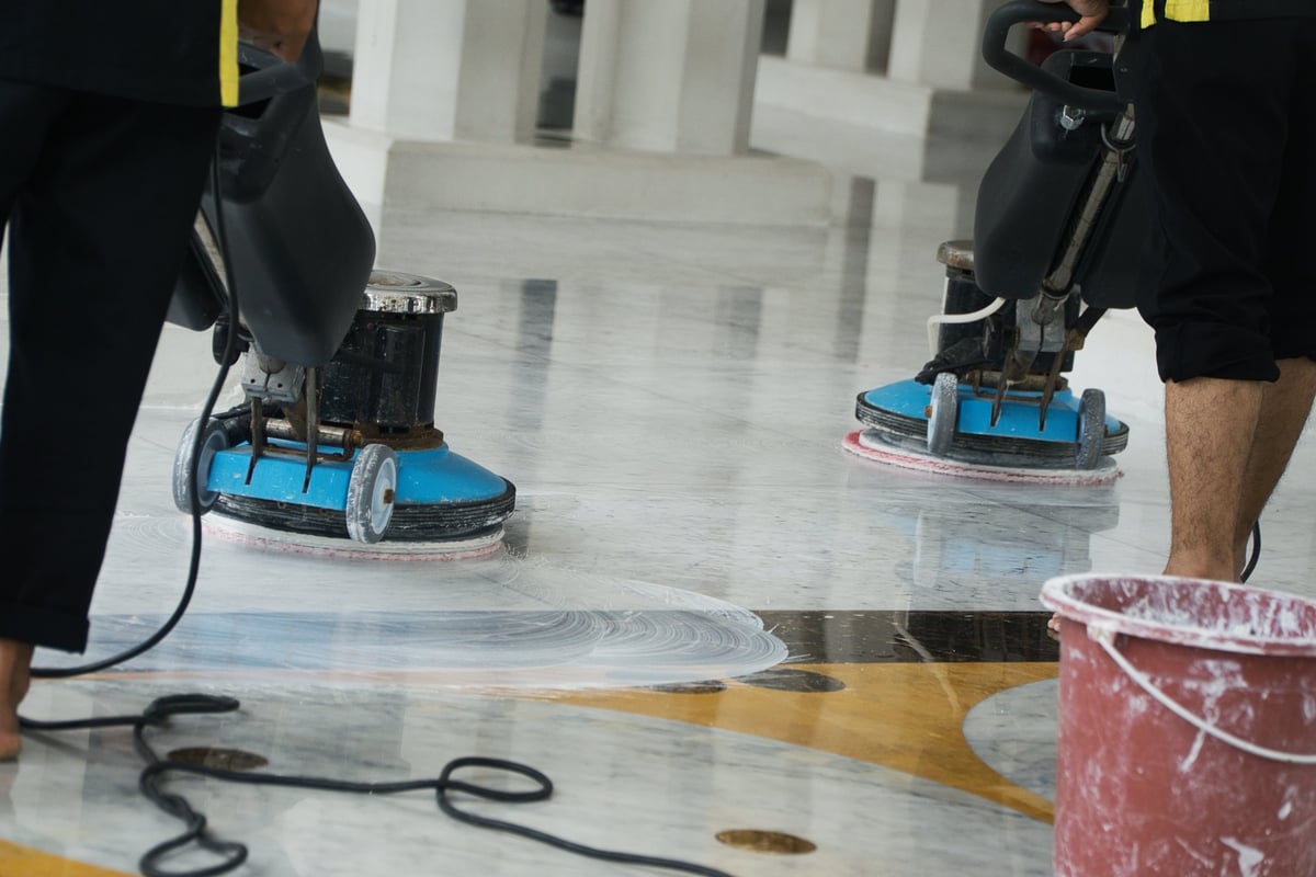 Technicians operating professional floor buffing machines on a polished marble commercial floor